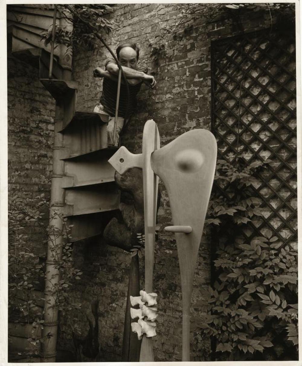 Isamu Noguchi in the courtyard of his MacDougal Alley Studio with "Bone Sculpture"