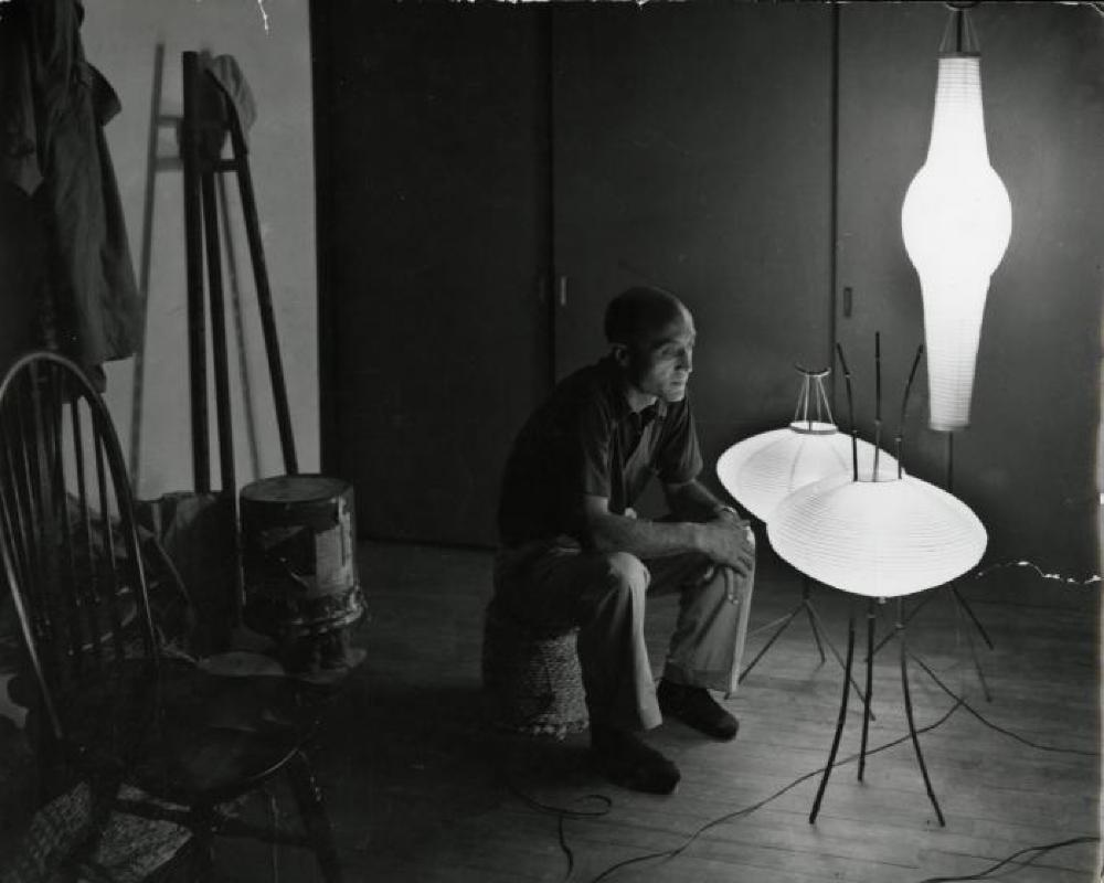 Isamu Noguchi seated with three Akari