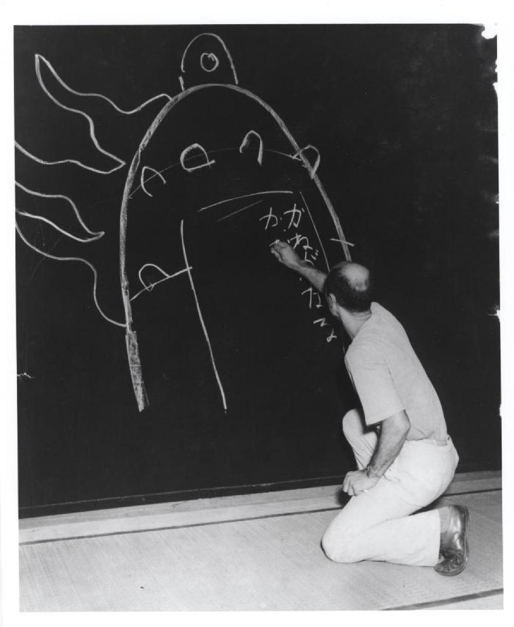 Isamu Noguchi writing his father's poem "Kane ga naru" at his exhibition at Mitsukoshi Department Store, (Nihombashi Head Store), Tokyo,  August 1950