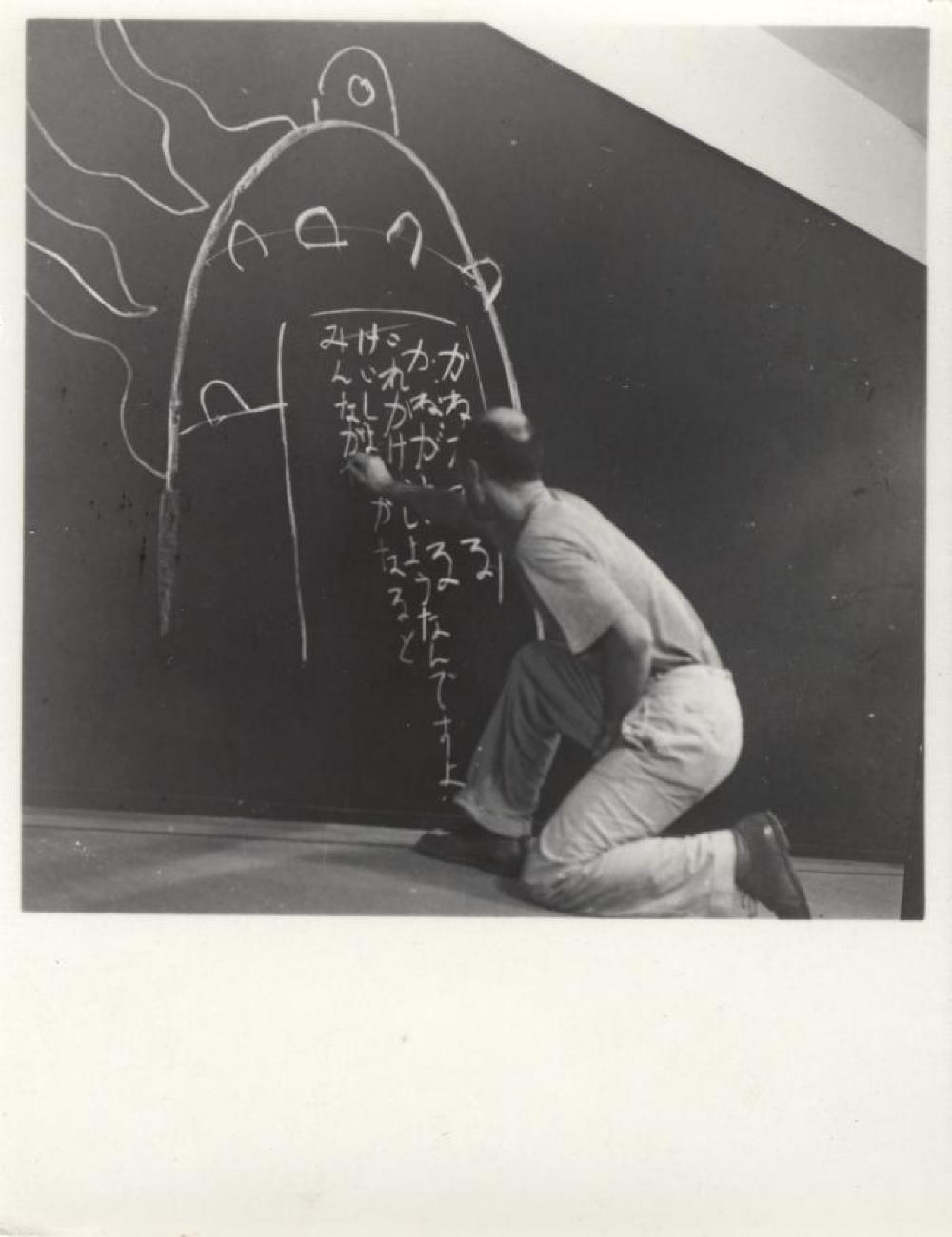 Isamu Noguchi writing his father's poem "Kane ga naru" at his exhibition at Mitsukoshi Department Store, (Nihombashi Head Store), Tokyo,  August 1950